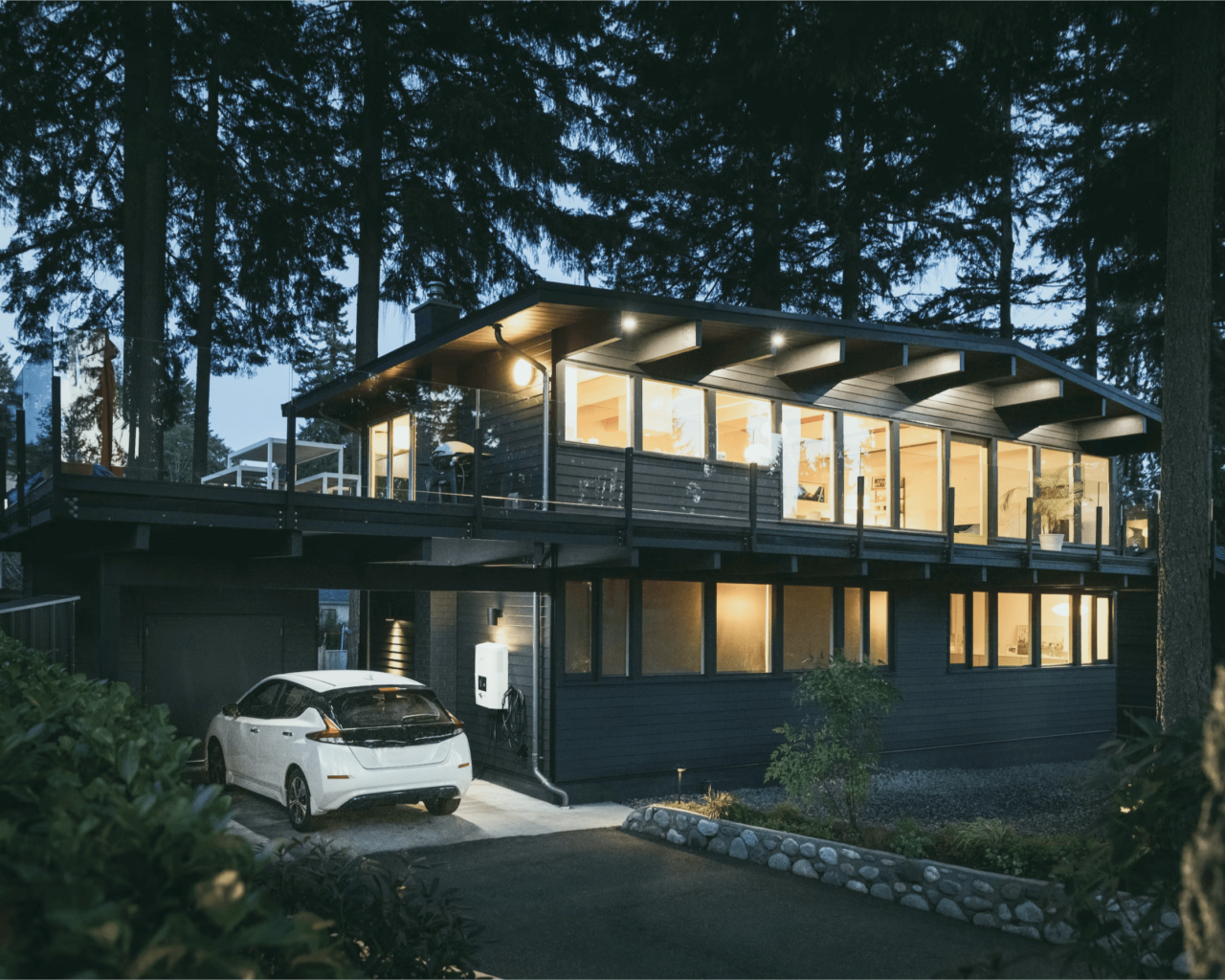 Modern home surround by forest with an electric charging station in the car port